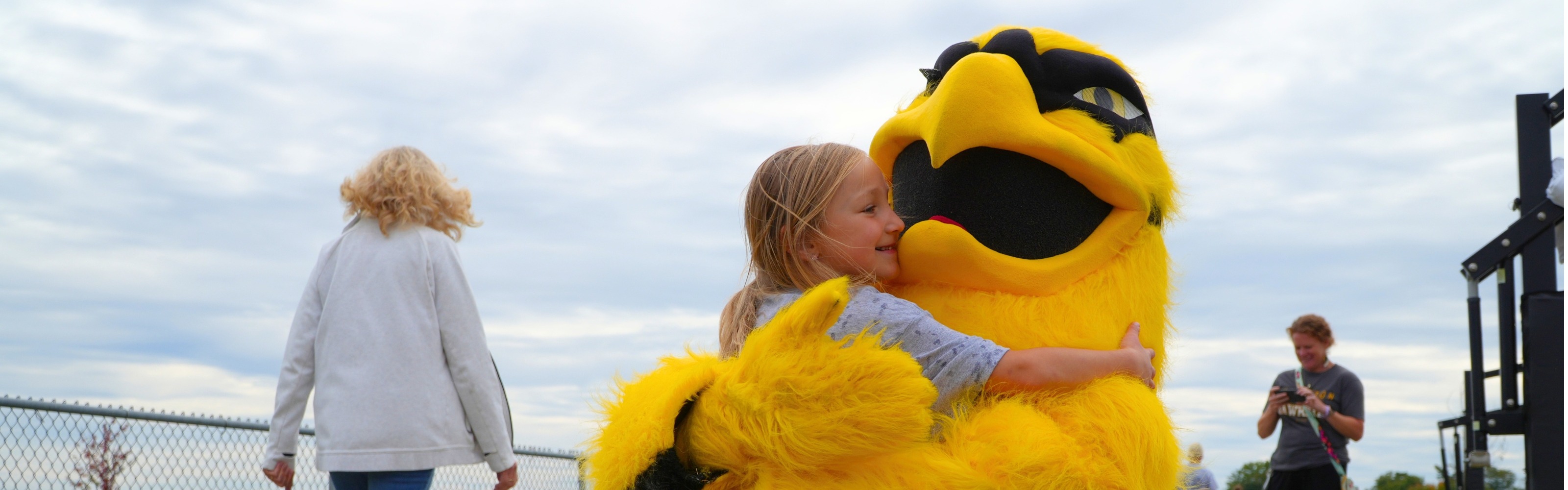 A female student hugs the yellow mascot.