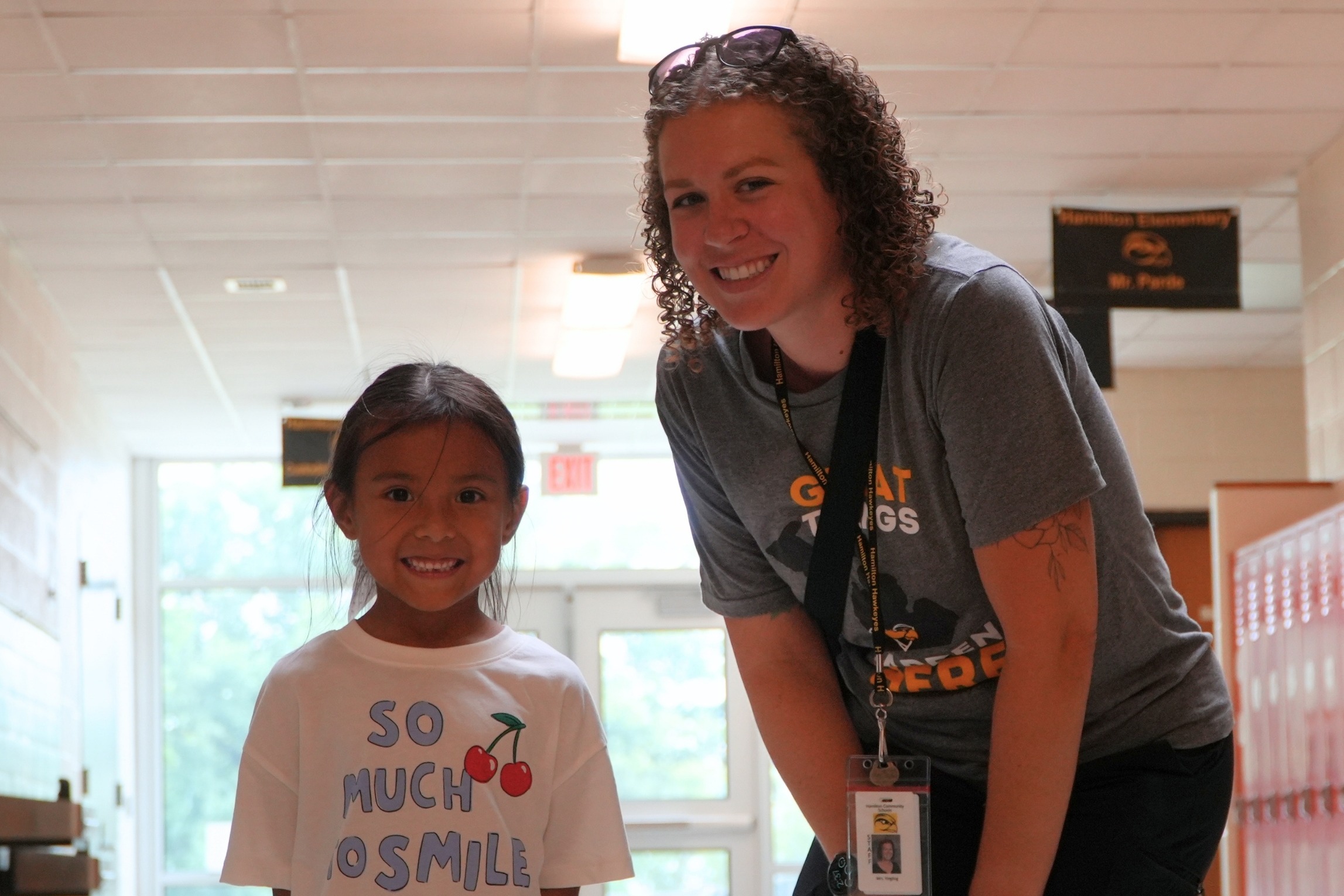 A female student with a female staff member smiling in a hallway.