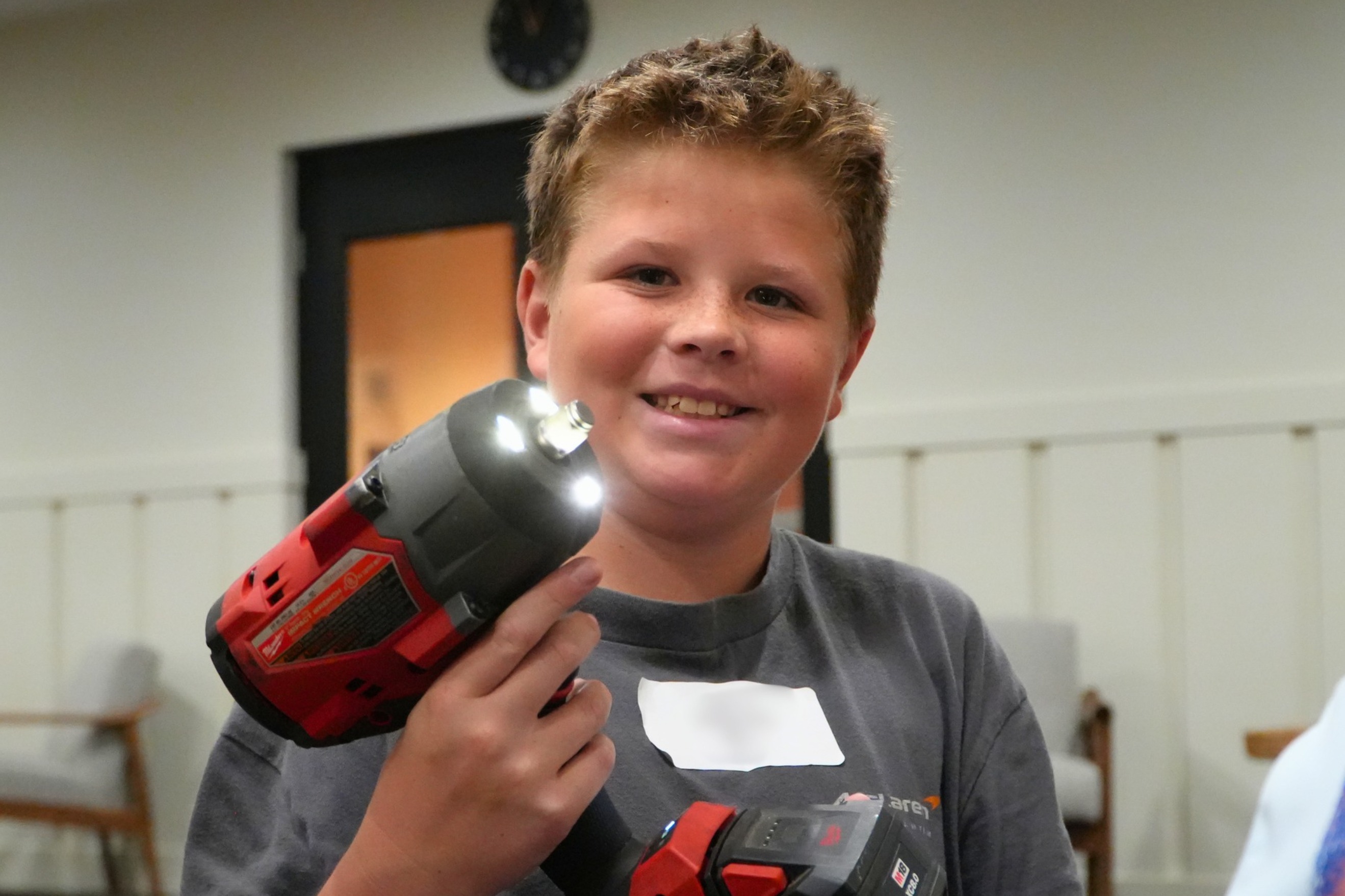 A male middle school student holds up a drill.