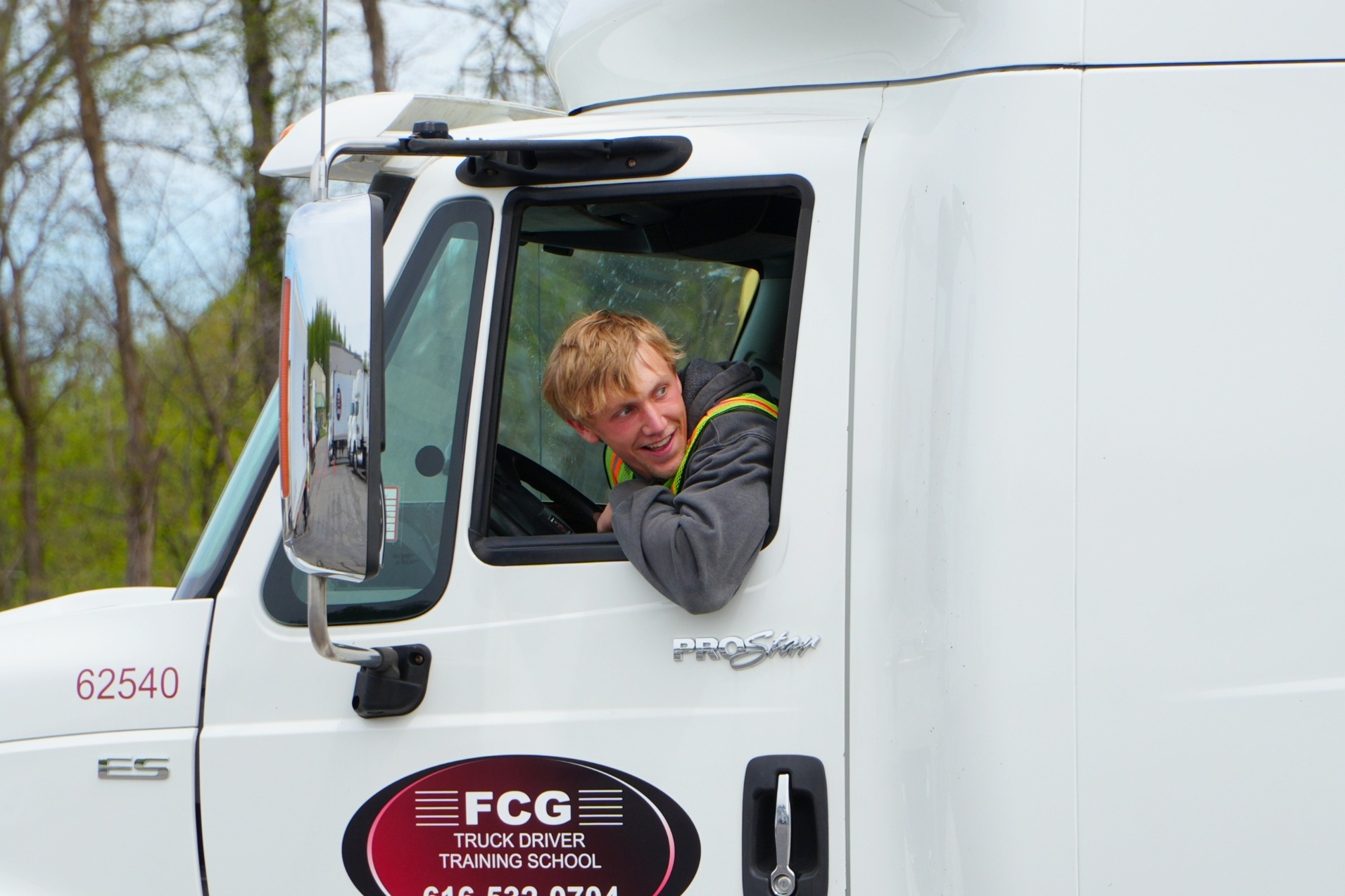 A male Hamilton student smiles as he looks out the window of a semi backing up.