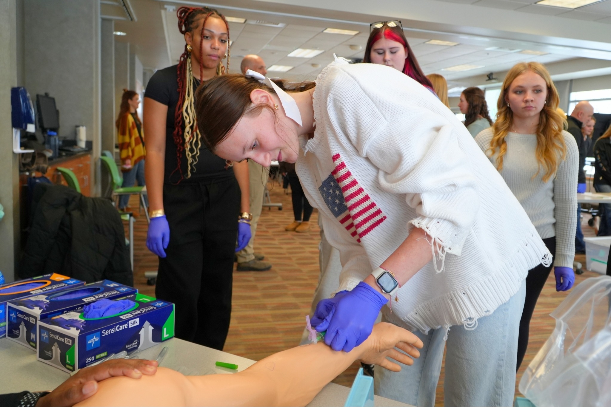 A female student learns about the medical field with students around her.