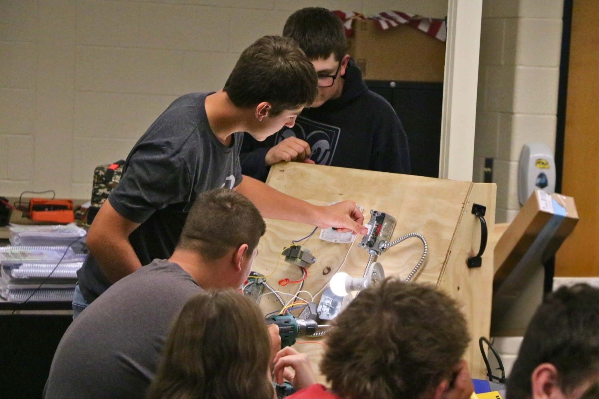 A male student turns on a light switch on a control panel.