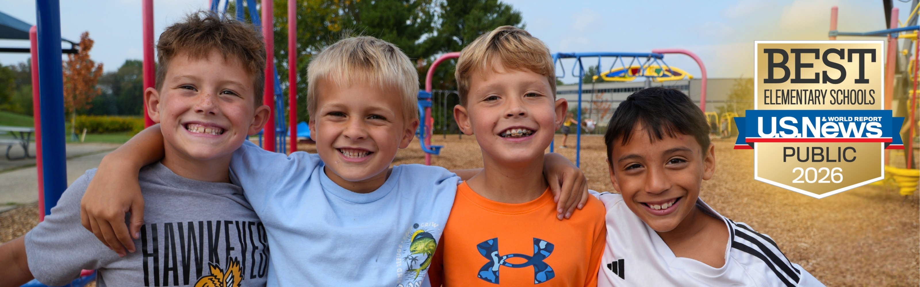 Four male students smile on the playground.