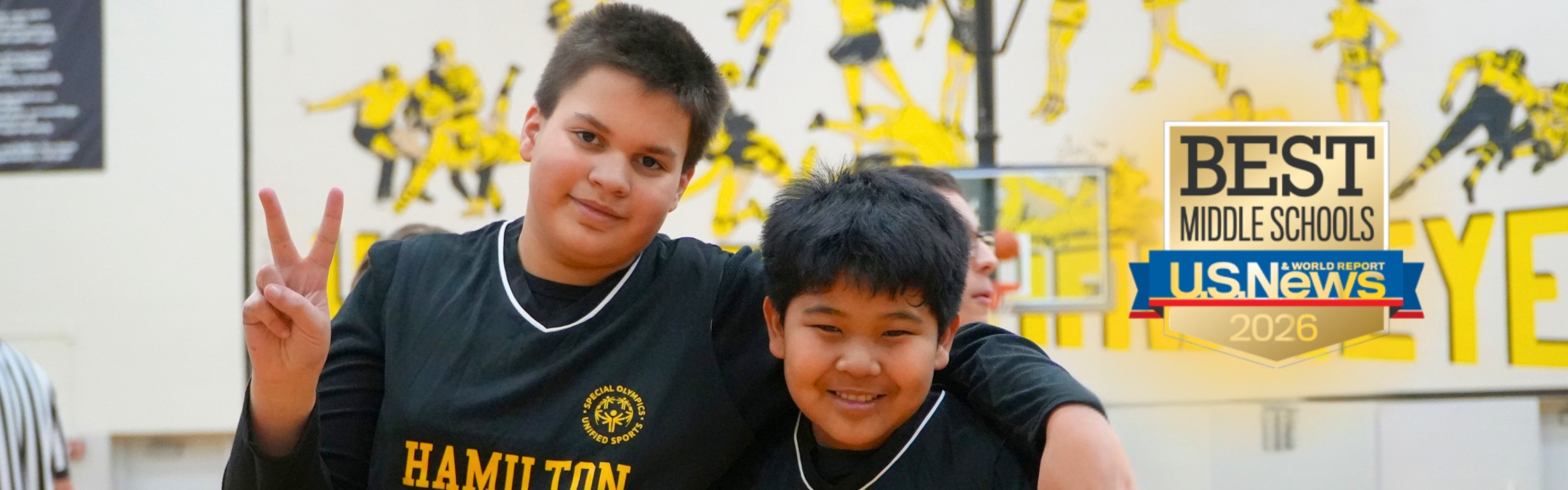 Two male students smile together in basketball jerseys.