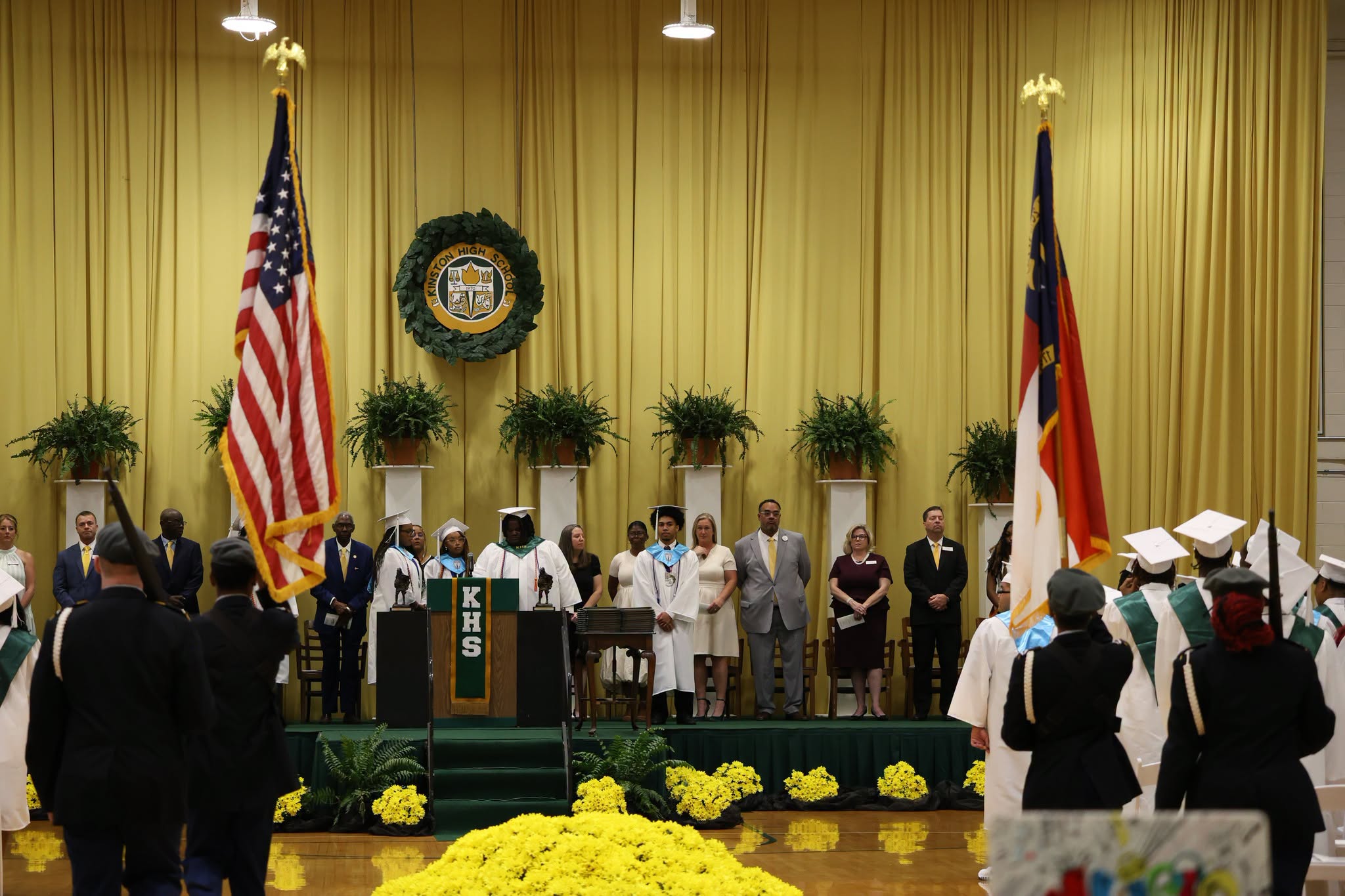 students stand at graduation