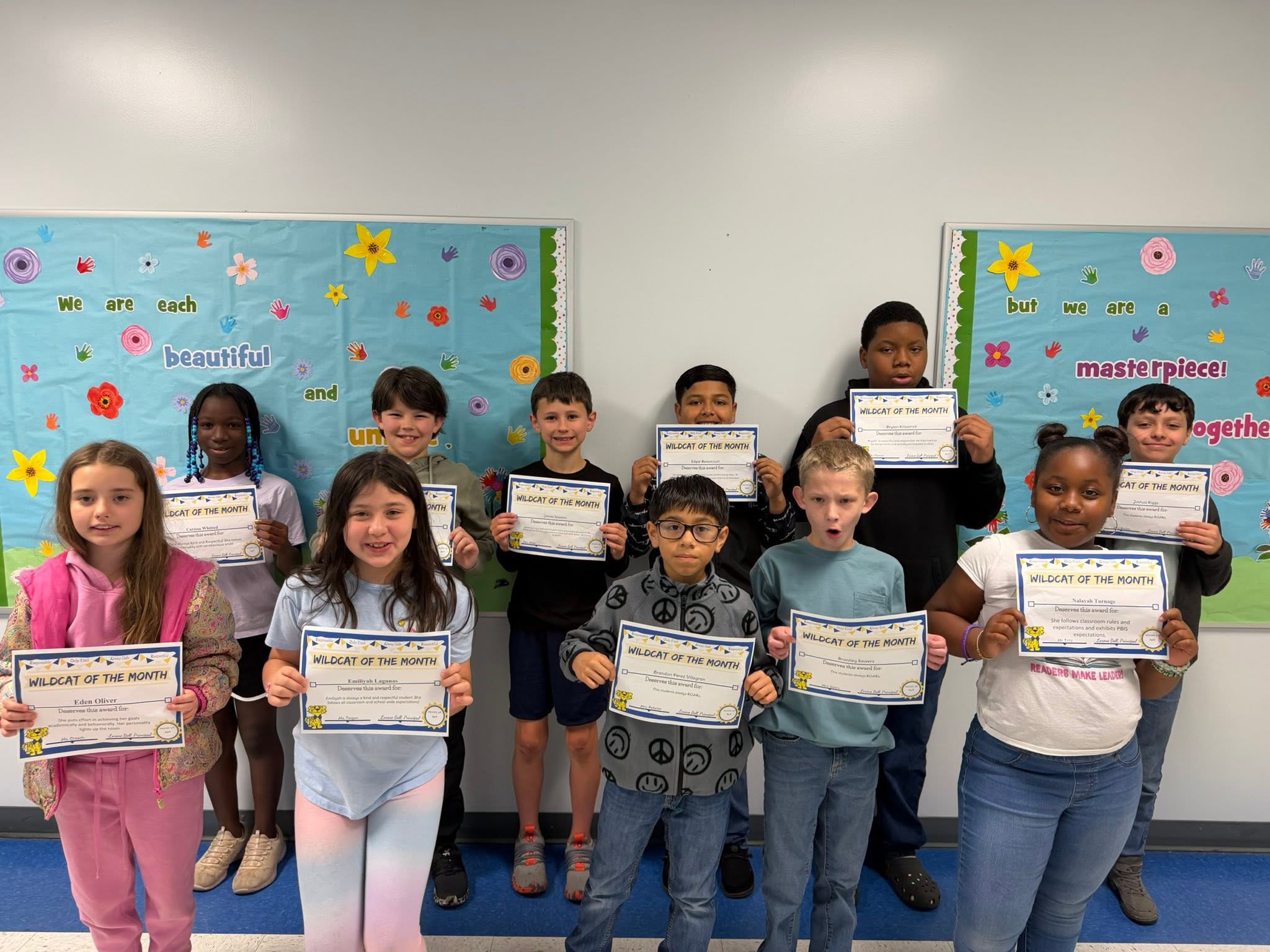 Students of the month stand smiling with certificates