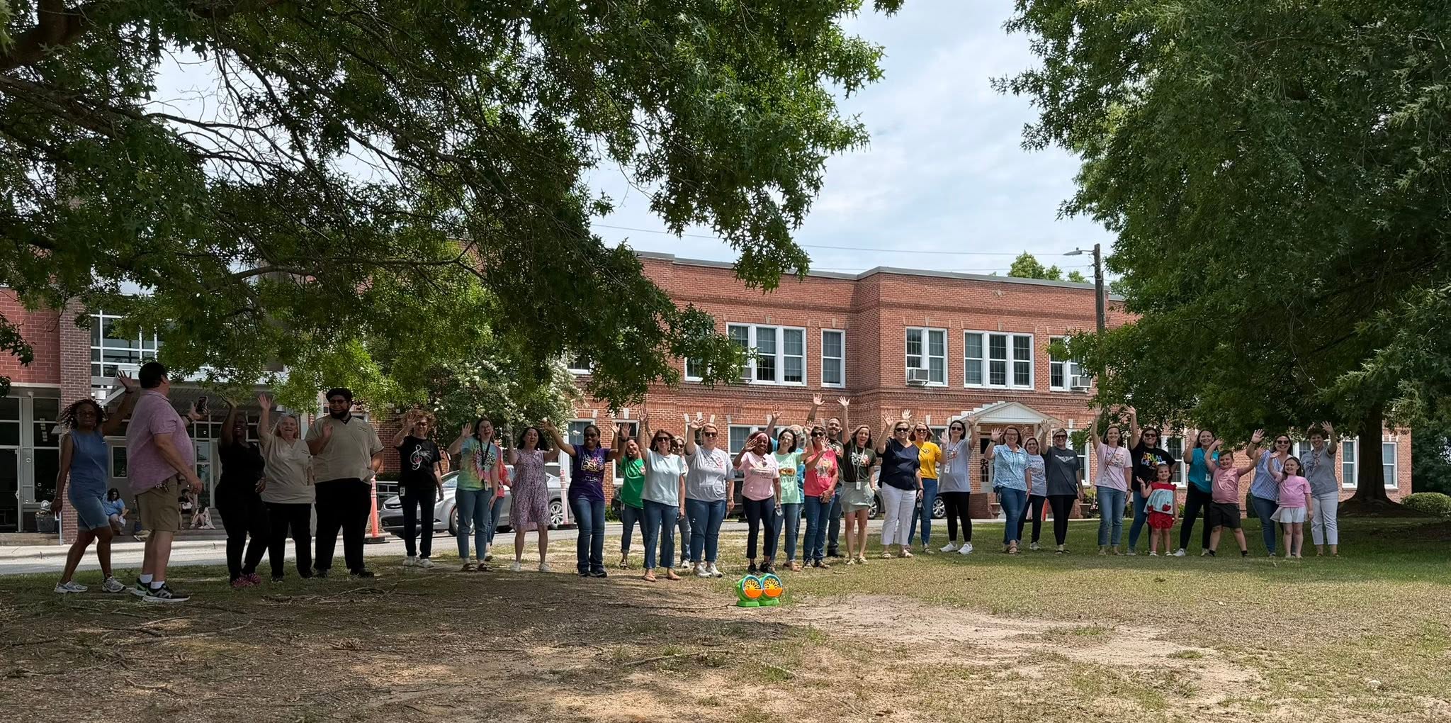 teachers wave goodbye in front of the school