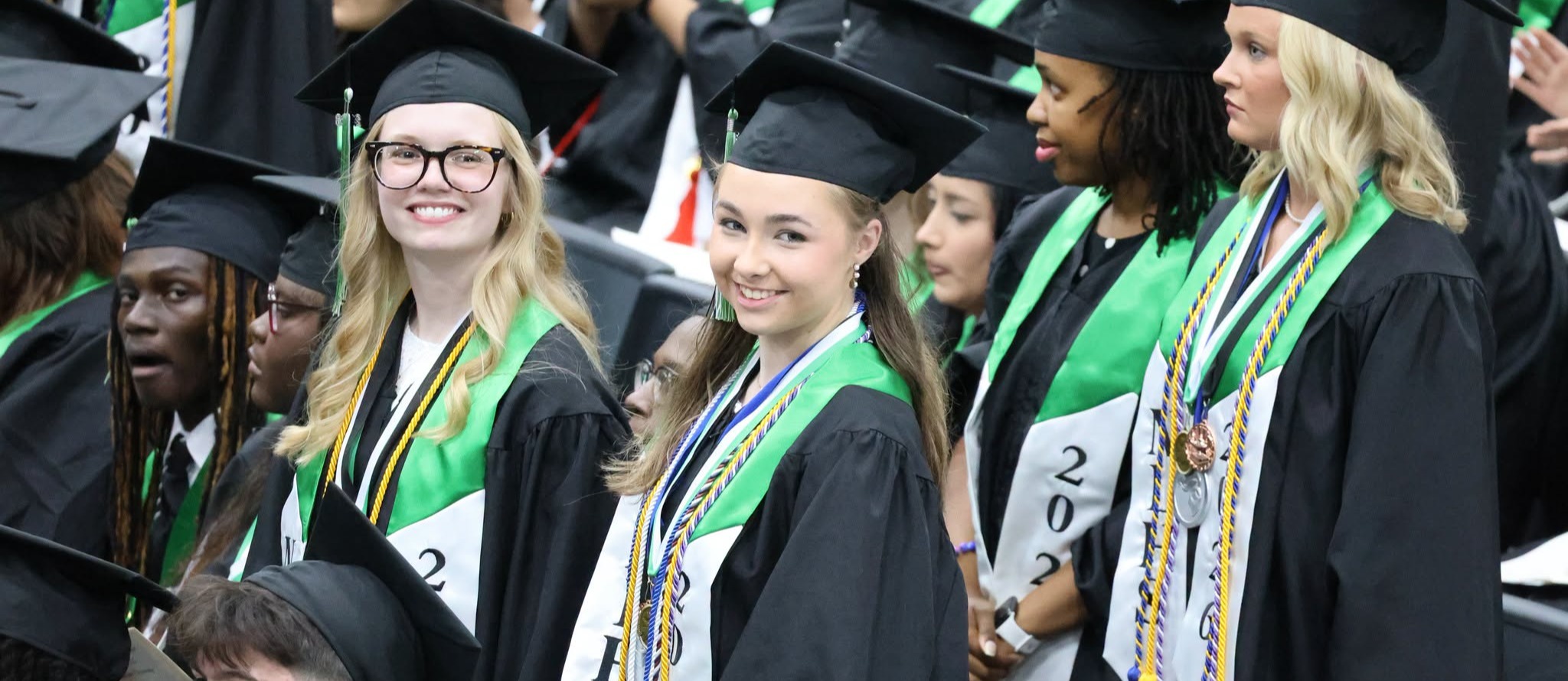 two graduates smile into the audience