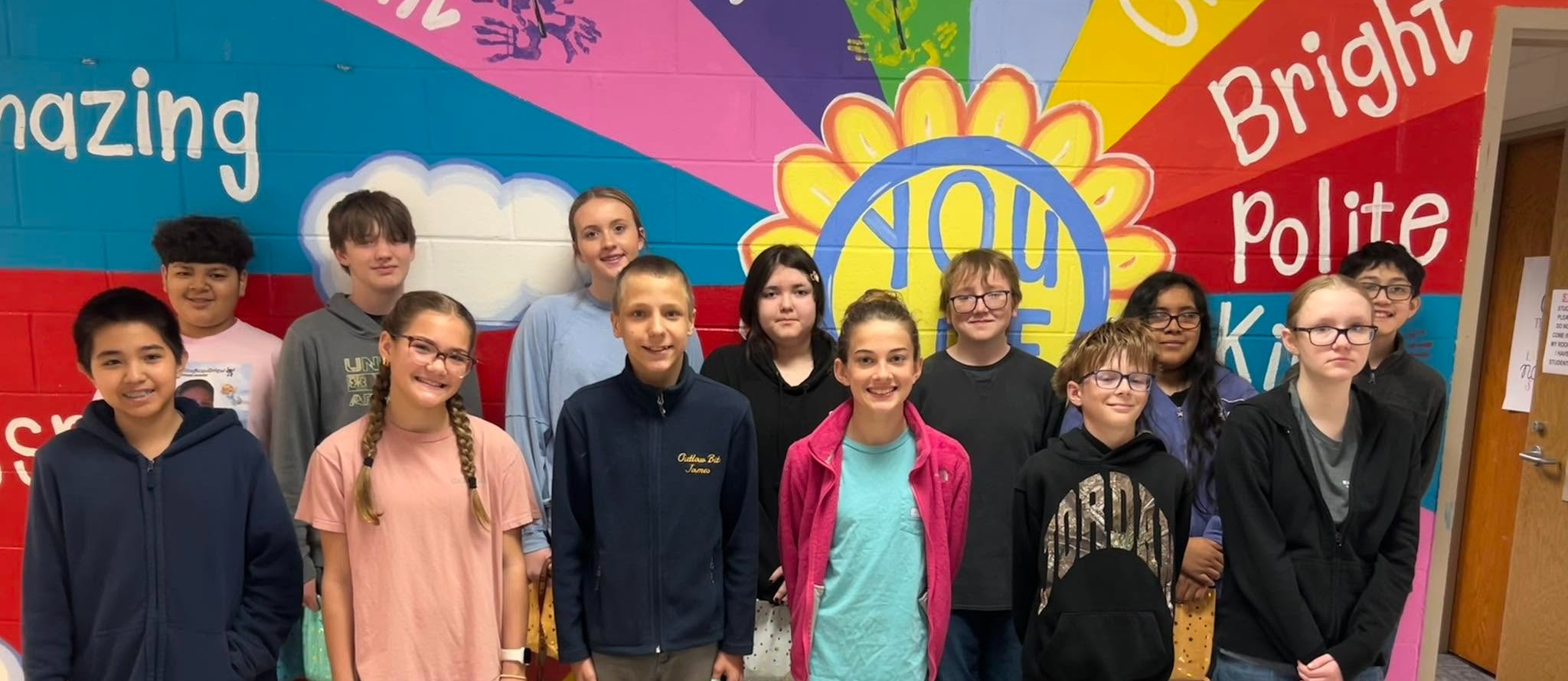 Students stand in front of a painted mural