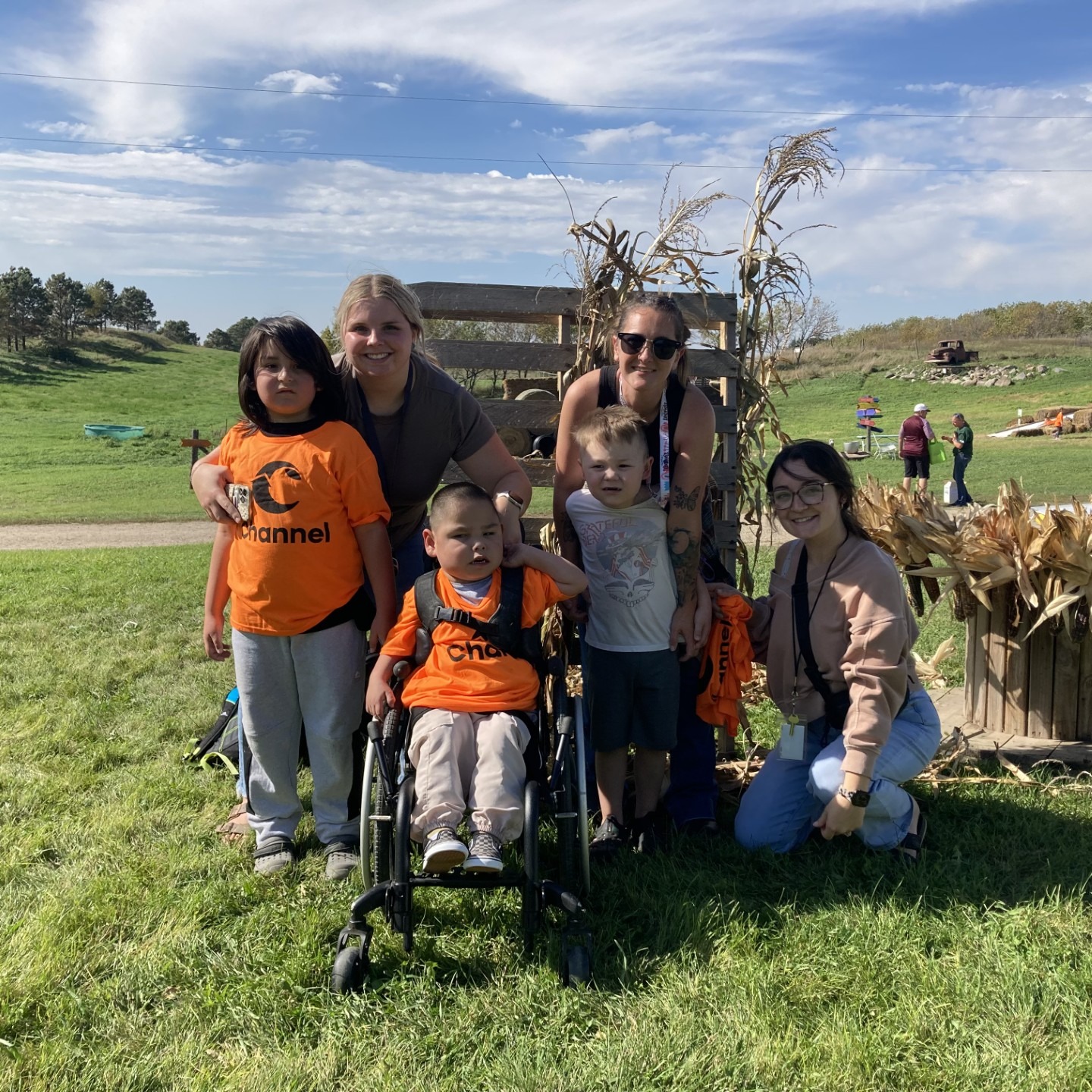 Three young students with paraprofessionals at a pumpkin patch. One student is in a wheel chair