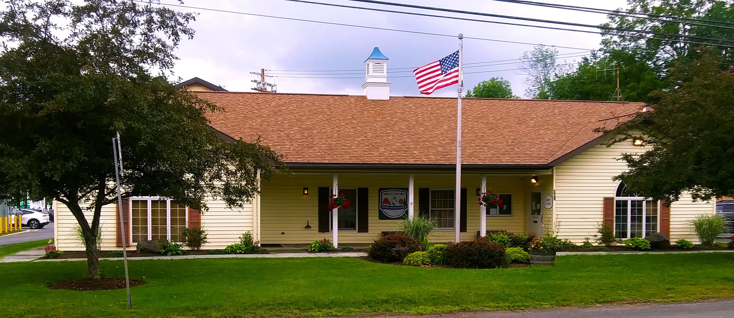 town of hancock office - yellow with a brown roof and an american flag