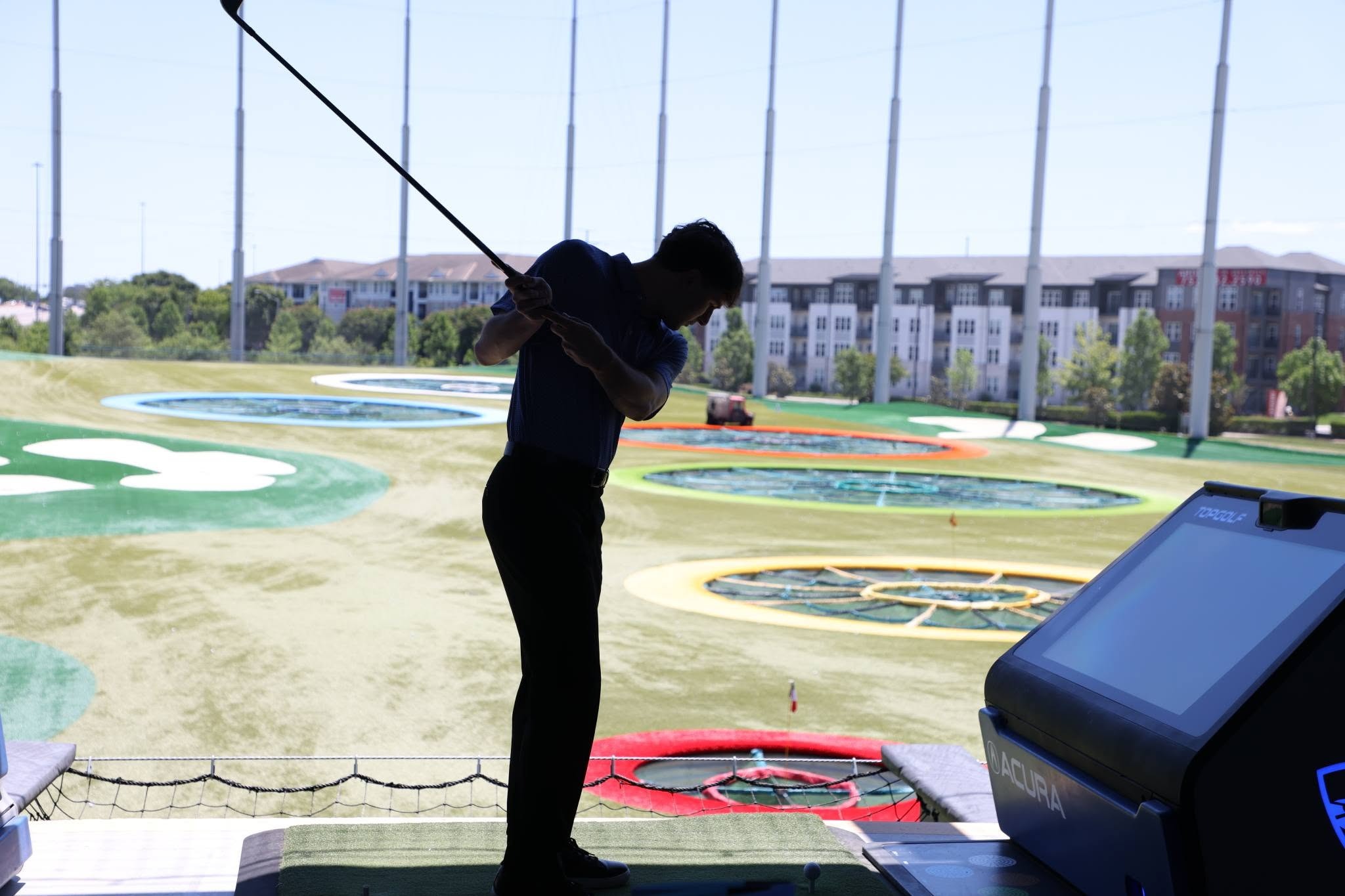 Shilloutte of a person hitting a golf ball at Top Golf