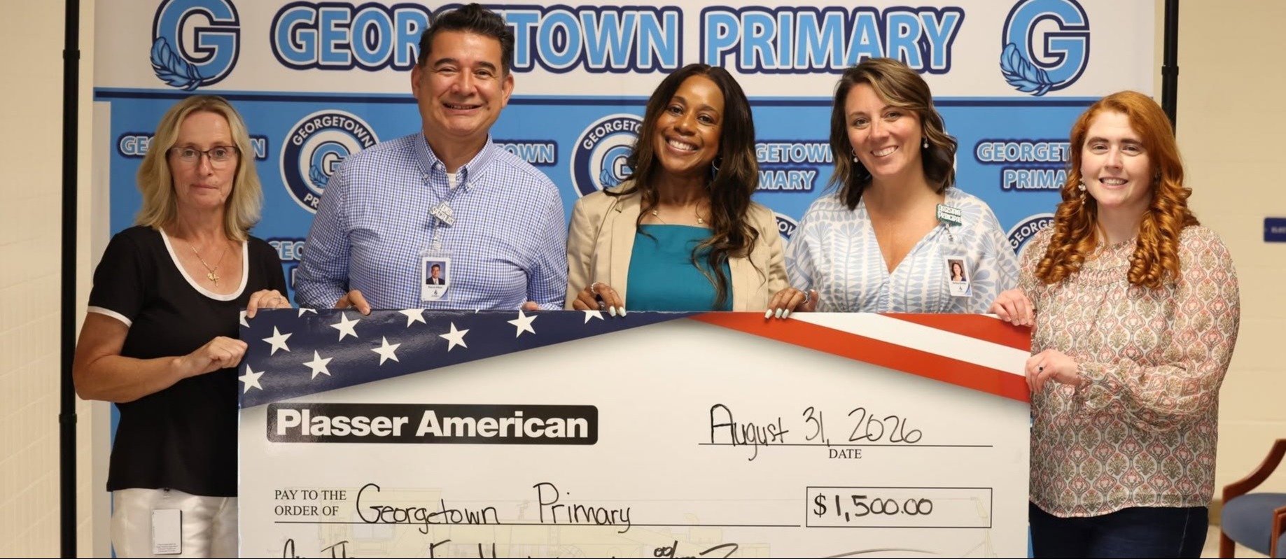 Teachers hold a large check for a donation from Plasser American