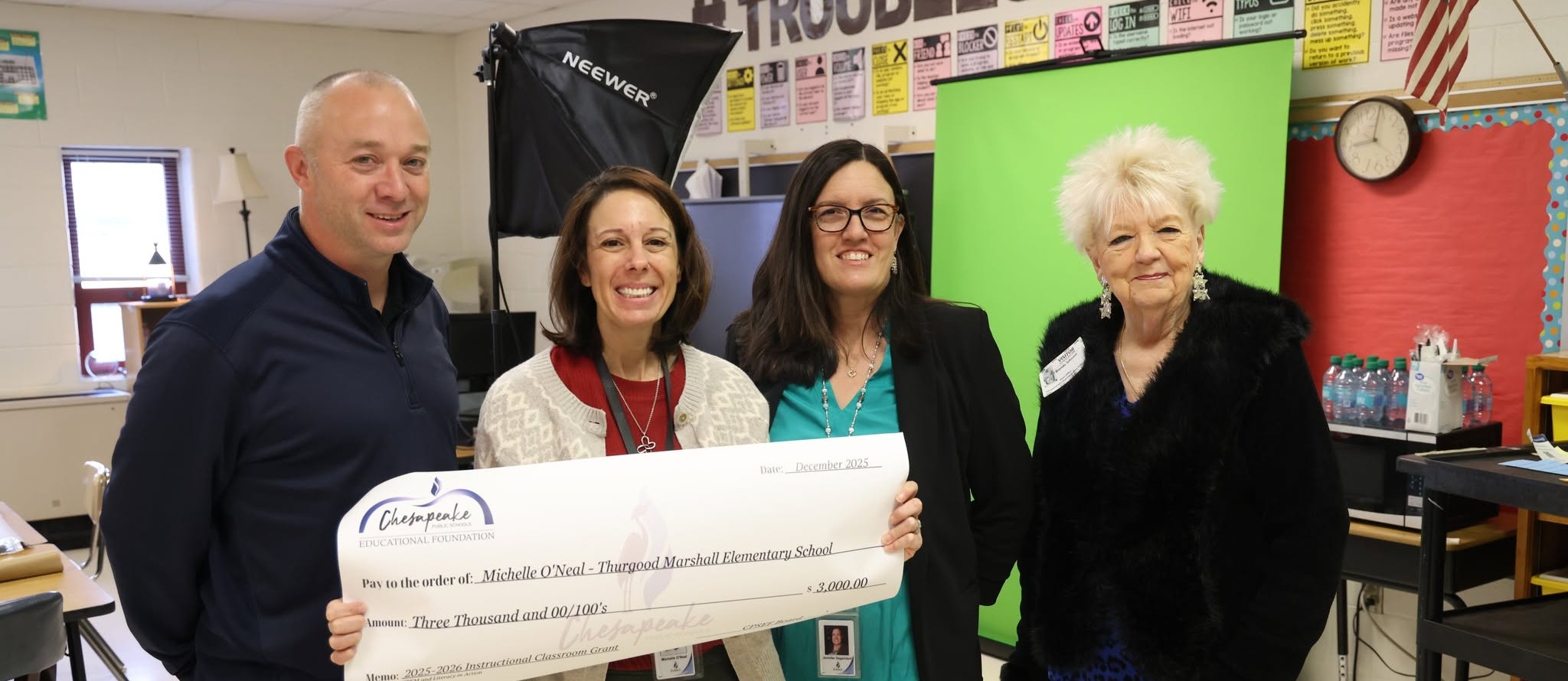 Group of 4 people holding up a check