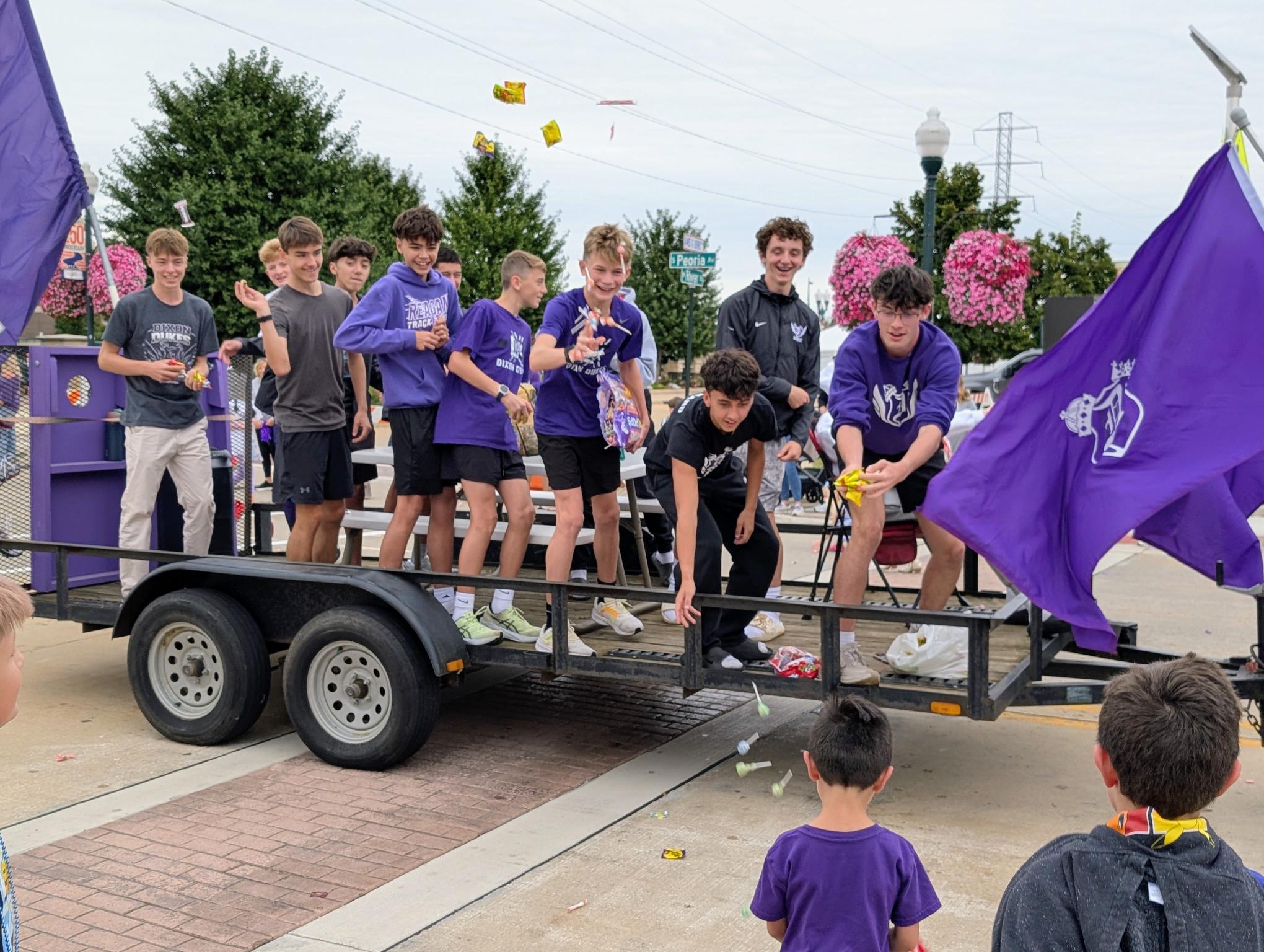 students riding homecoming float tossing candy to kids