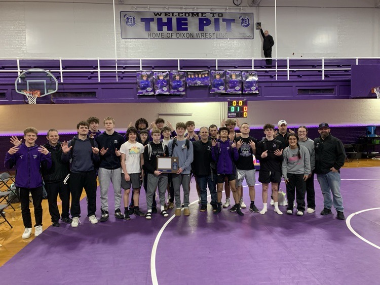 wrestling team posing with conference championship plaque