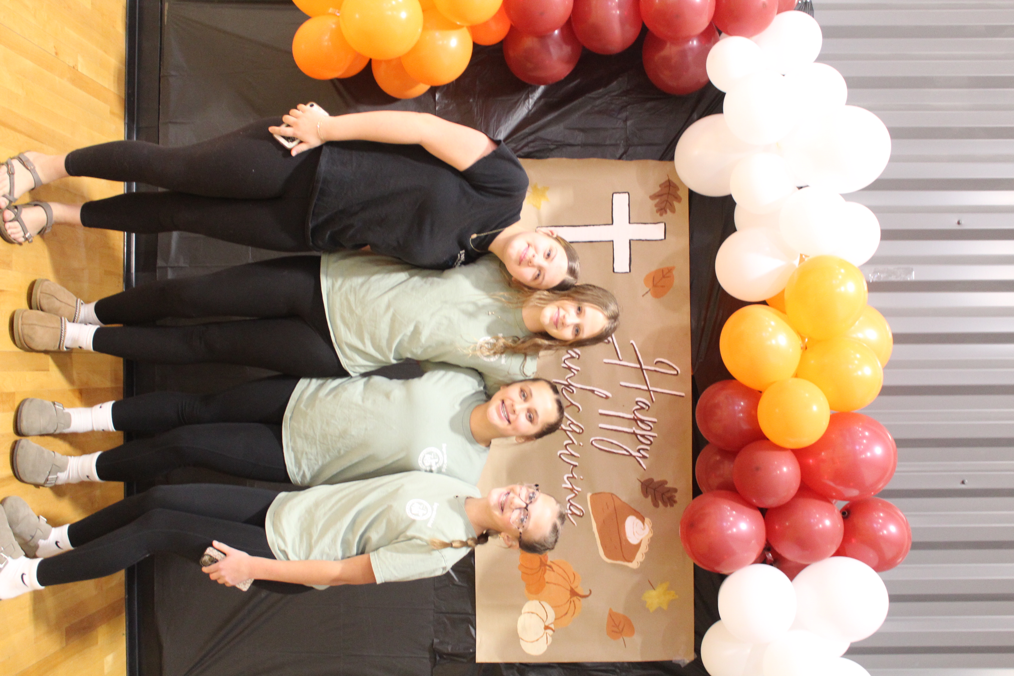 students smiling in front of FCA thanksgiving backdrop
