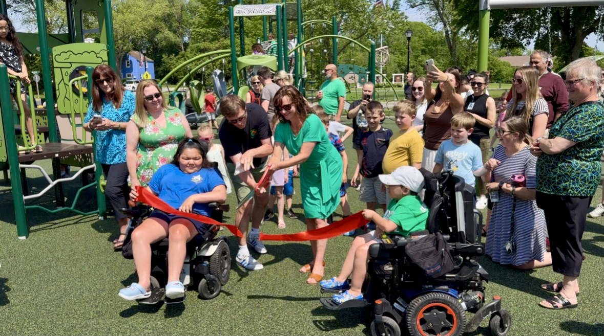 Jaycee Park ribbon cutting with students in wheelchairs holding the ribbons and adults smiling and standing 