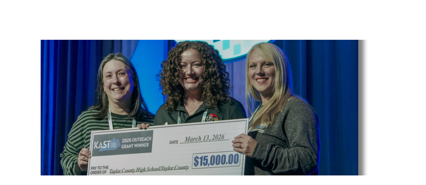 Three women holding a check that says "$15,000.00" in front of a blue curtain.