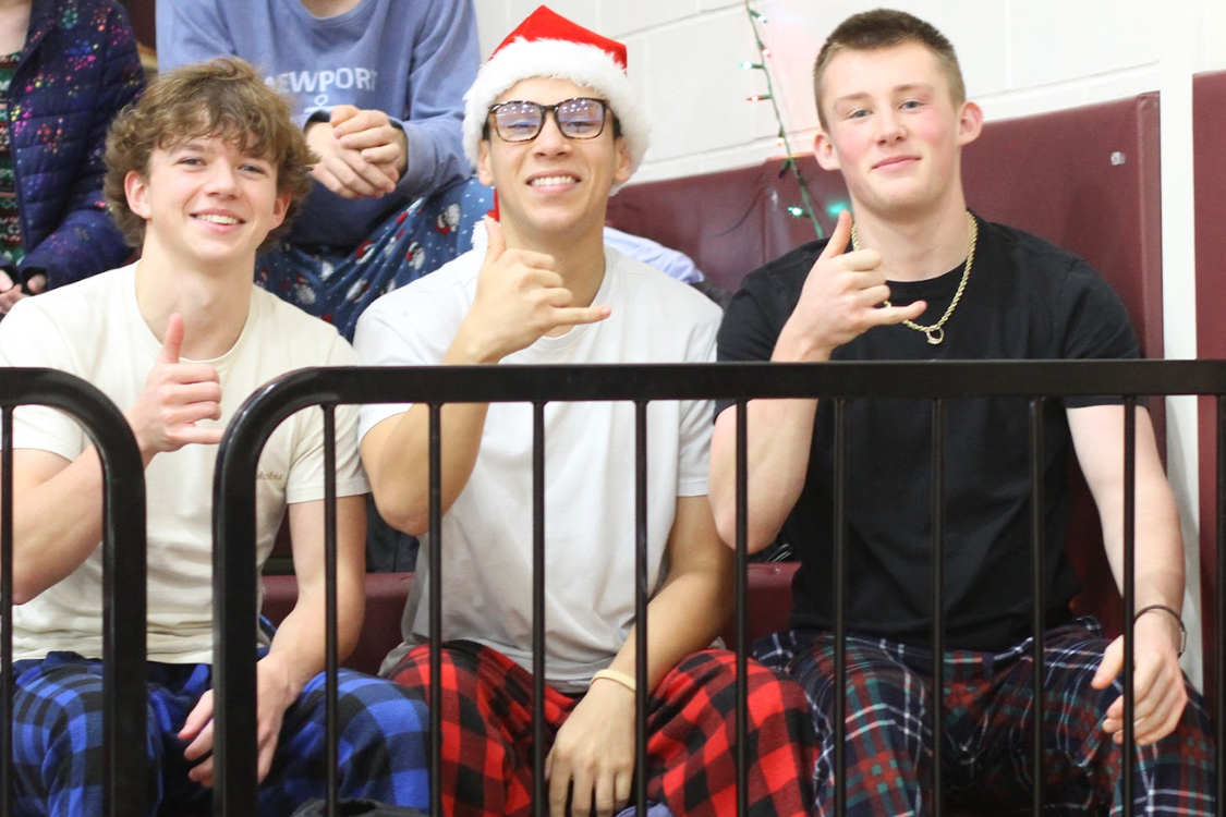 Four people, two in white shirts, one in a black shirt, sit behind a railing, smiling, and gesturing.