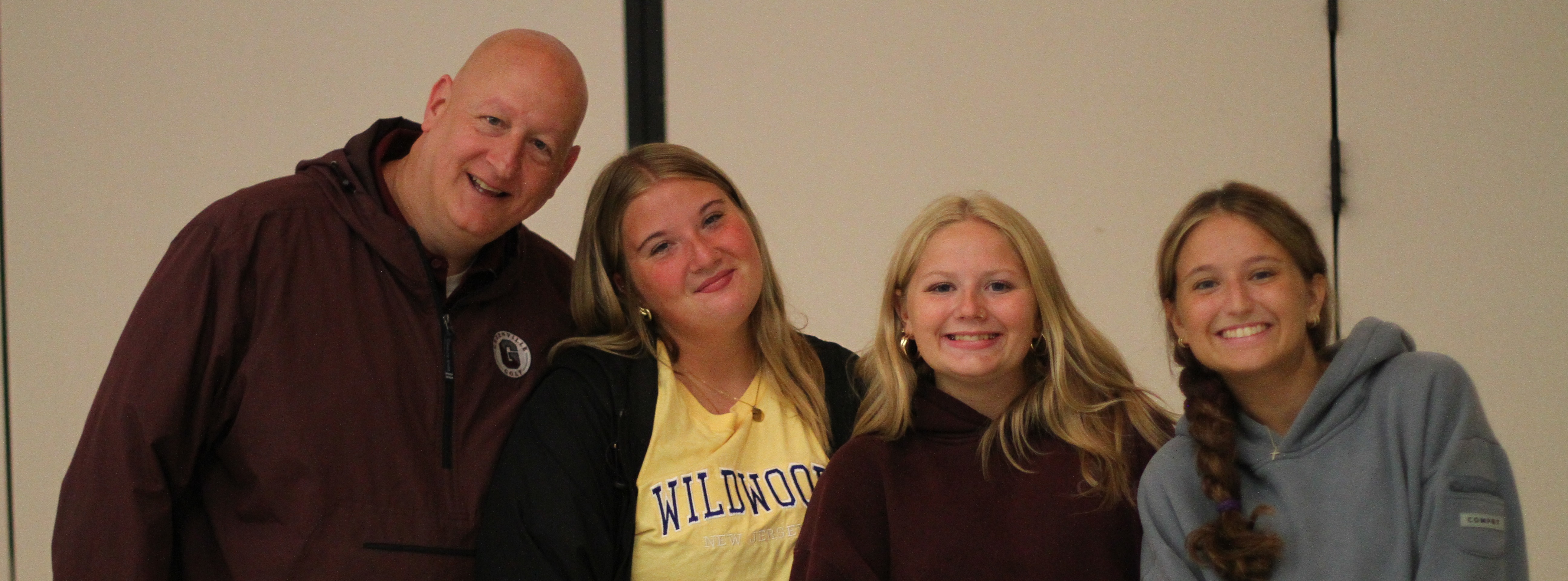 A group of four people posing for a photo. A man and three women. One holding a pen.
