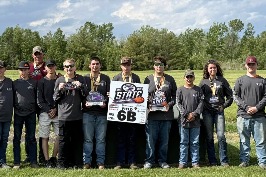 Group of people wearing medals, standing in a field with a sign reading 'STRIT 68'.