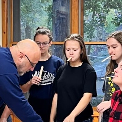 adult interacting with four teenagers as they are playing games using popsicle sticks