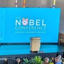 image of podium with "The NObel Conference" in teh background on a blue screen