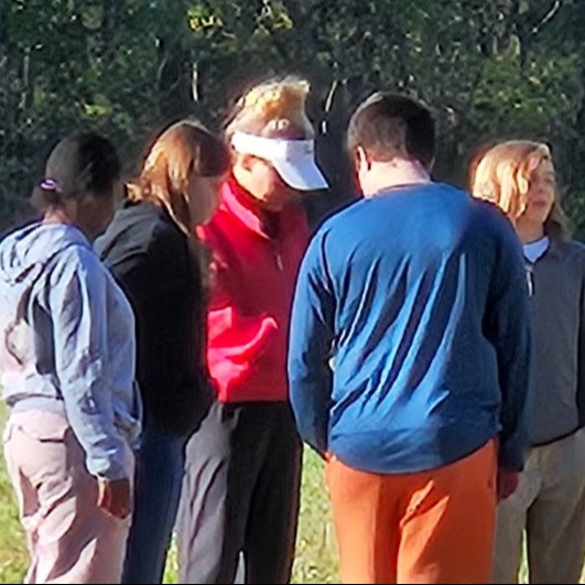 adult talking with students in a small group outide