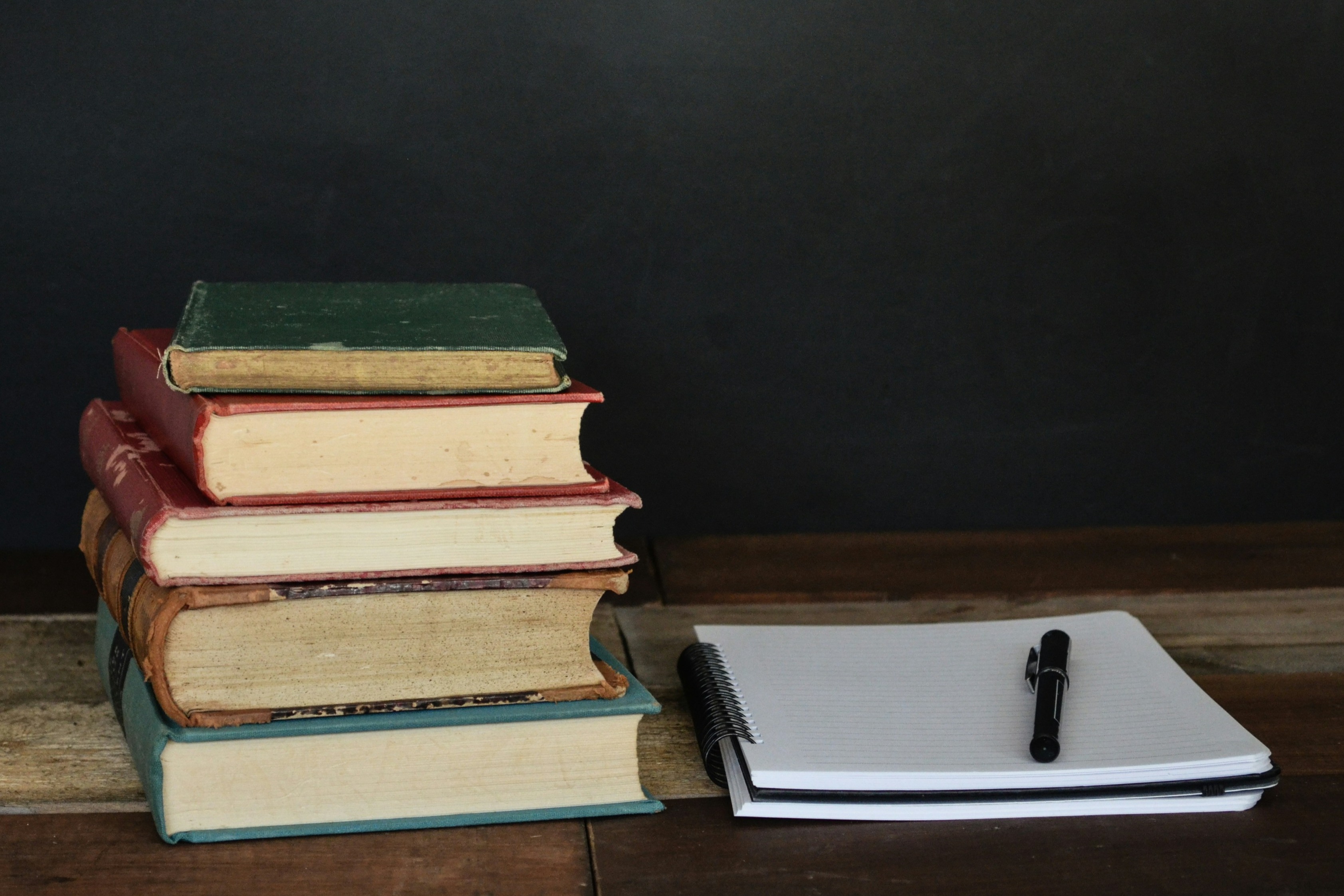 Image of books stacked with a notepad and pen next to it