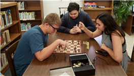A group of students playing chess at the library