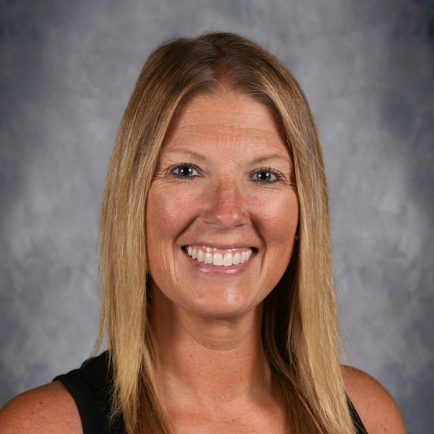 Woman with blonde hair and a black sleeveless top smiles against a gray background.