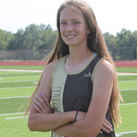 Student athlete poses in track uniform on football field