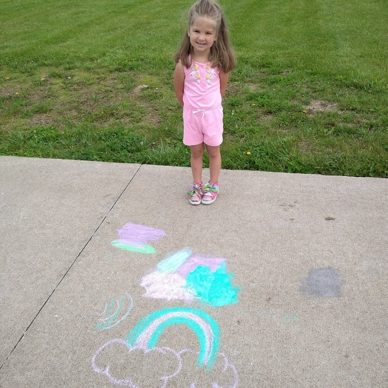 Young girl smiles with chalk art on playground