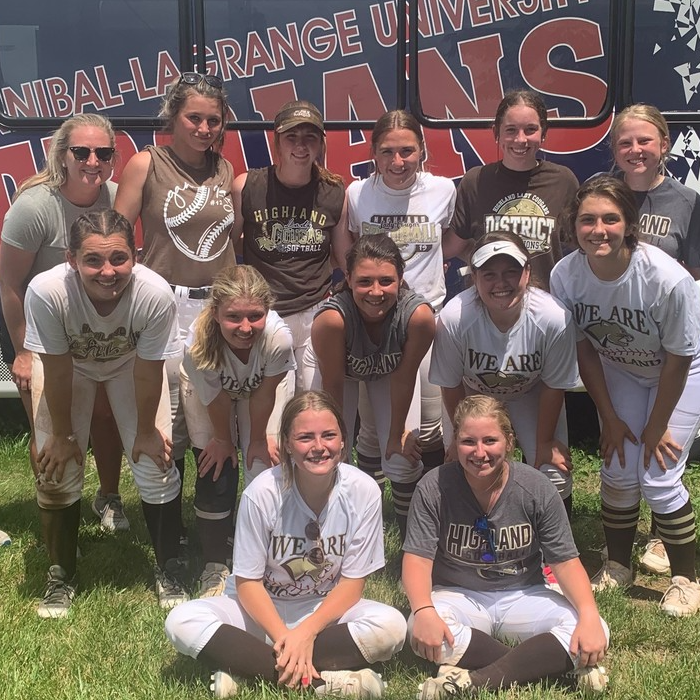 Team poses in front of bus