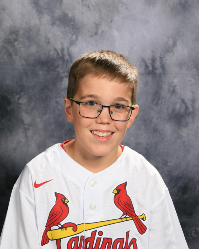 smiling boy with blonde hair and glasses in Cardinals jersey