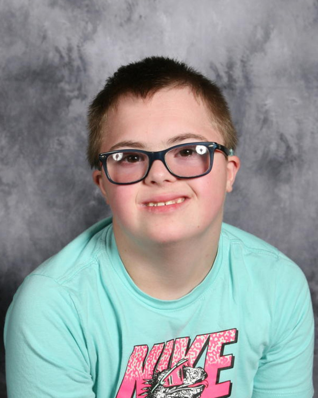 smiling boy with glasses and teal shirt