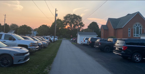 Cars parked along alley of church and in grassy area