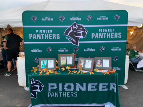 outdoor table set up with Pioneer Panthers logo and awards
