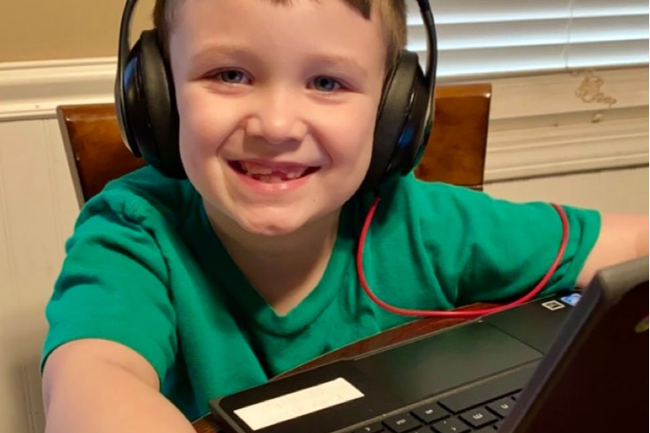 student wears headphones and works on Chromebook