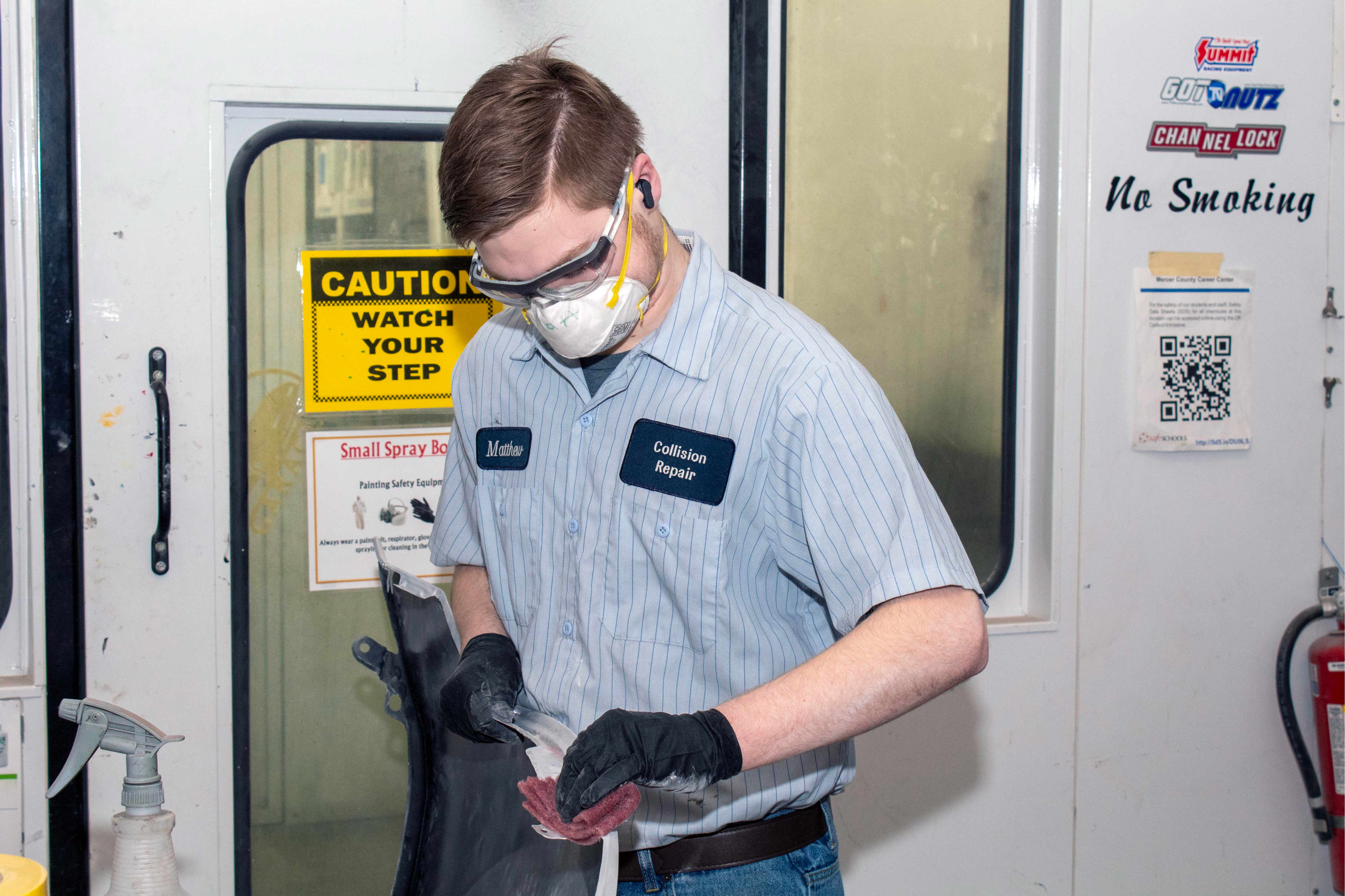 A student  puts finishing touches on a freshly painted panel.