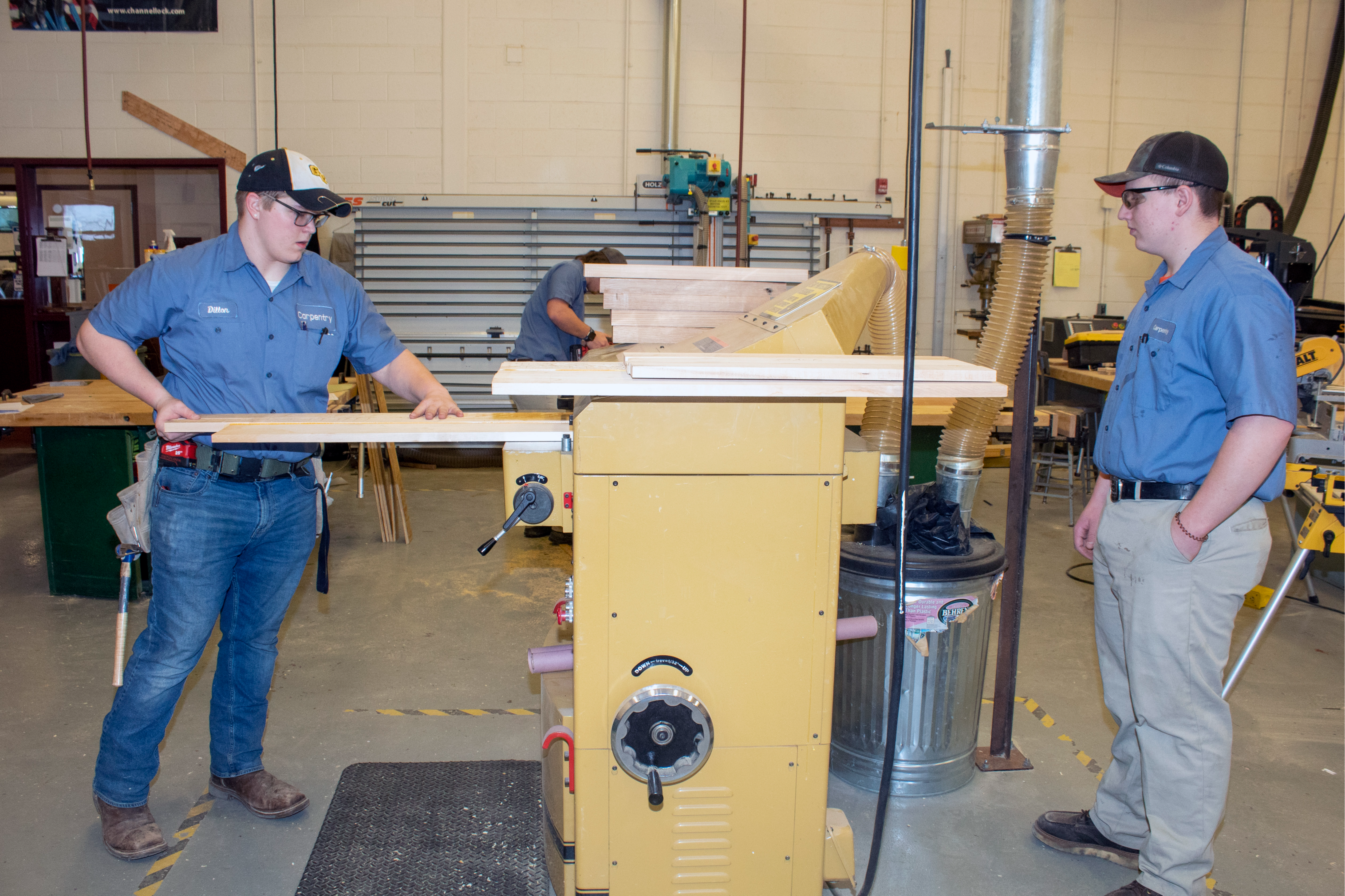 Students load wood into a horizontal  planer.