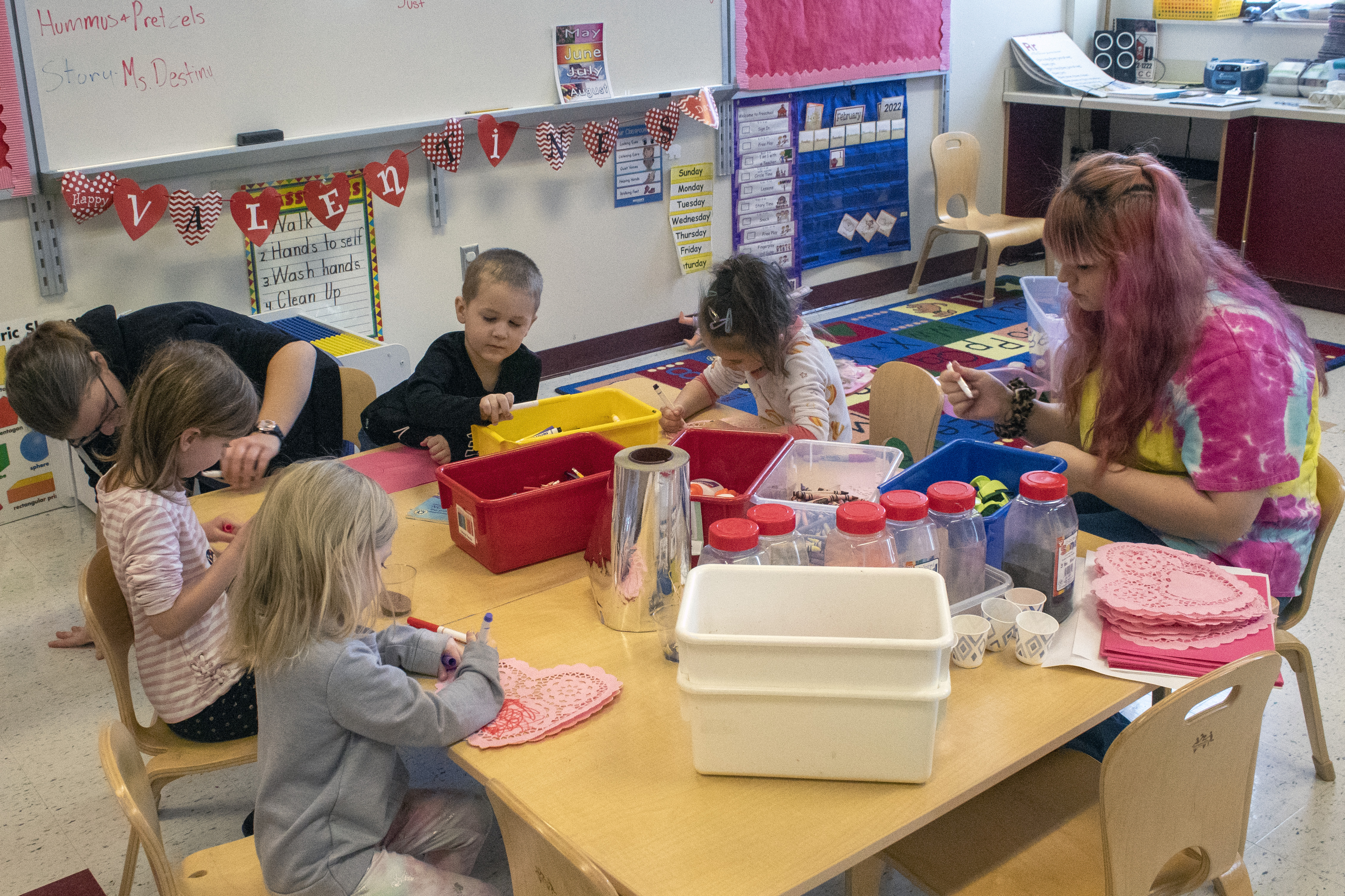 Preschoolers work on art projects guided by student teachers.