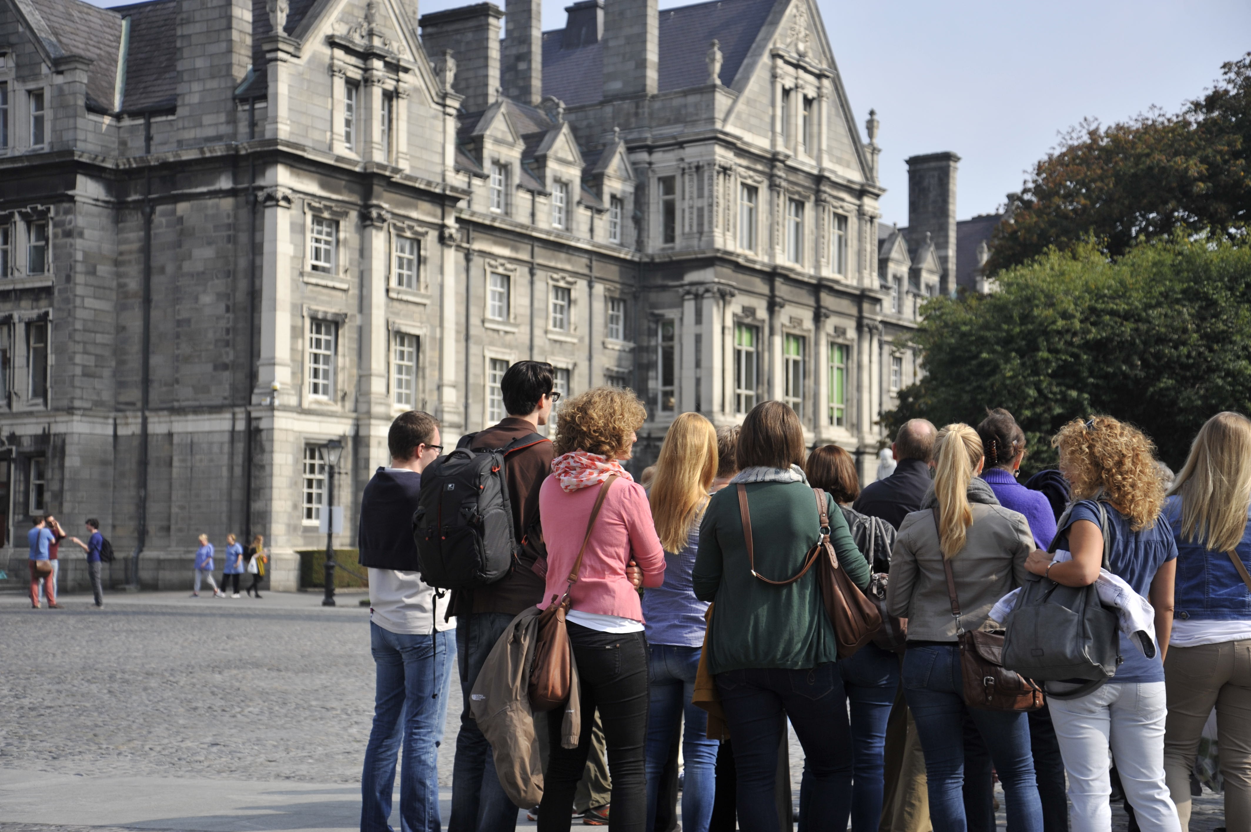 photo of a group of people standing in front of older building on a college campus