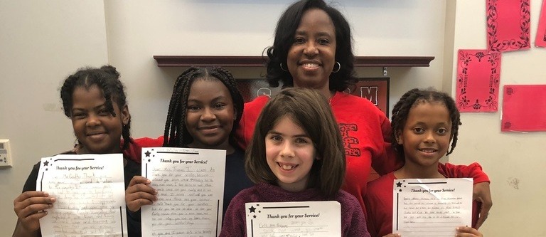 A principal with her students holding an assignment