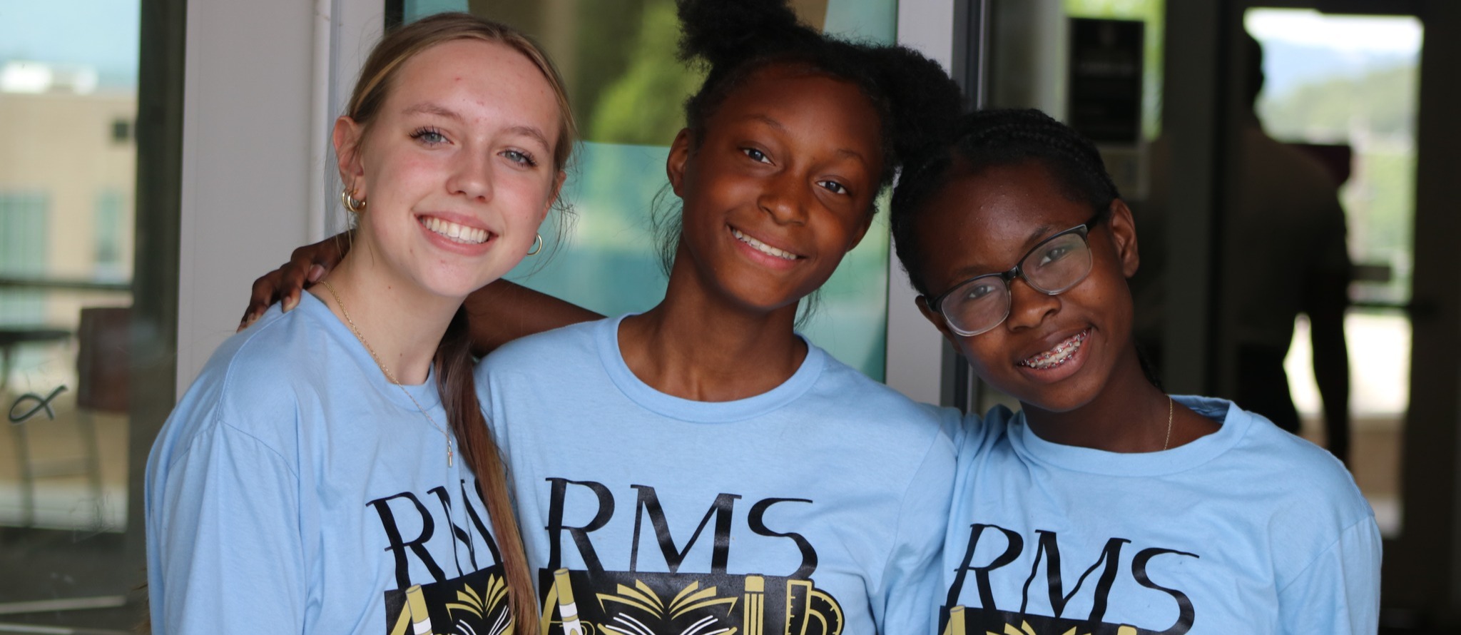 Three students in RMS AVID clothes smiling at the camera.
