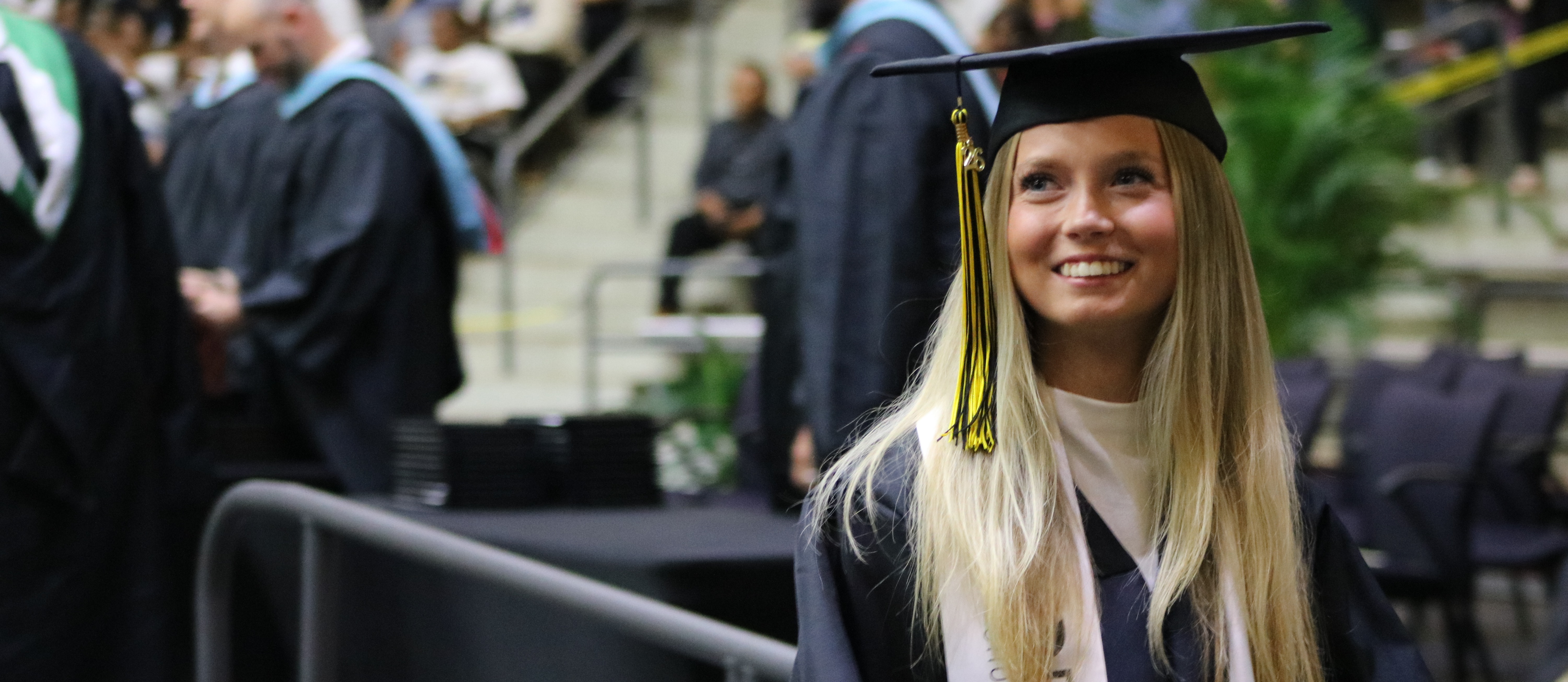 A student in graduation regalia looks over her shoulder.