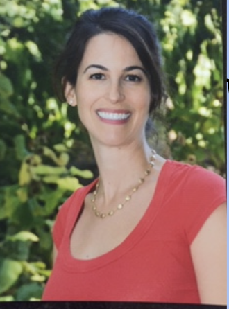 Jessica Miller wearing a red shirt standing in front of green foliage