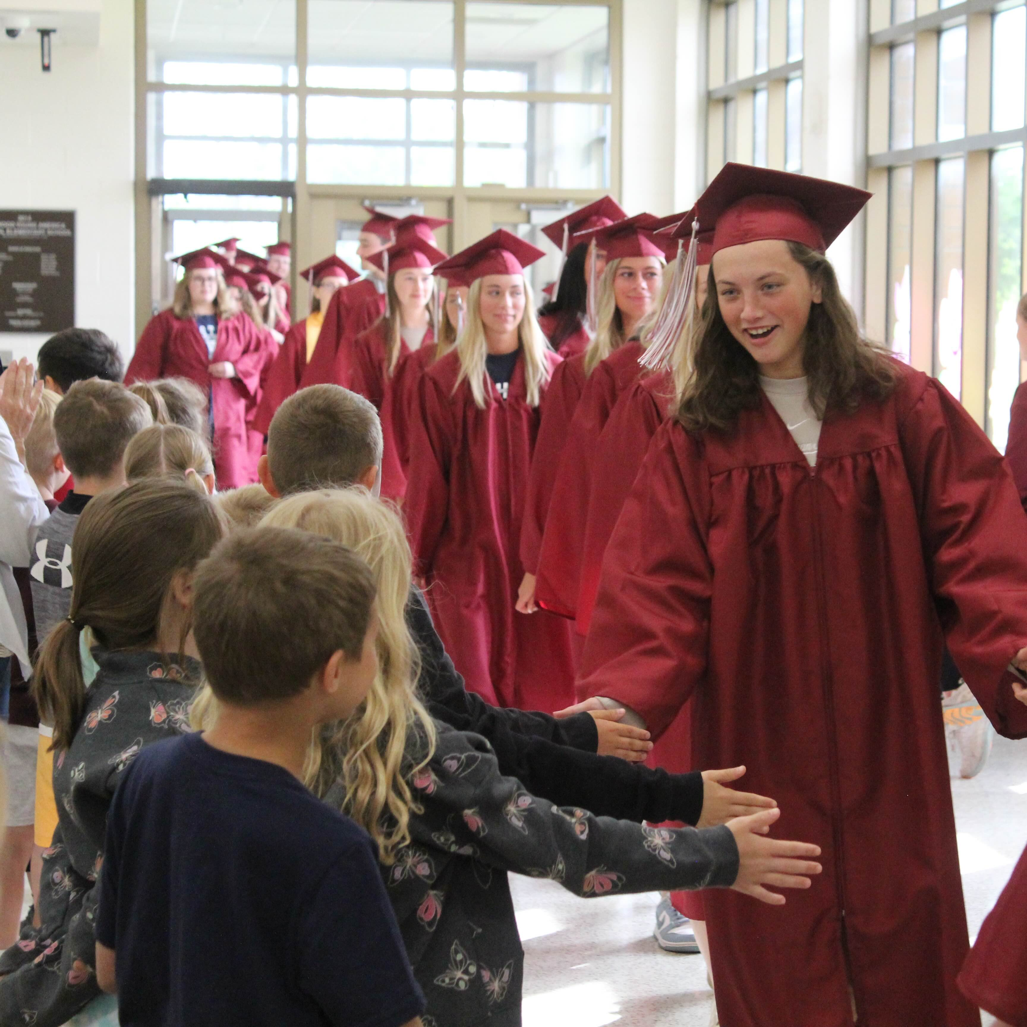 Graduates giving high fives to elementary students