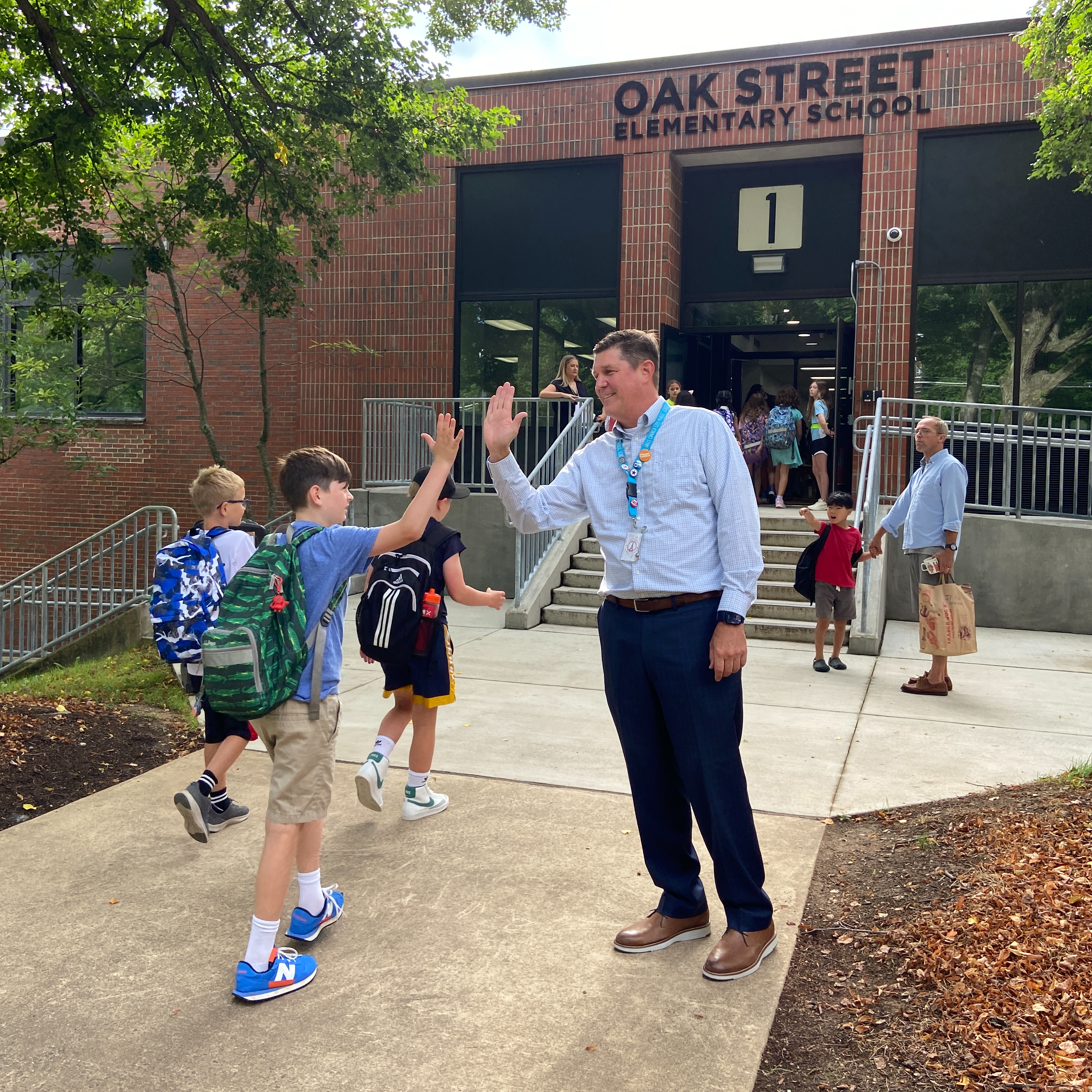 Dr. Noonan high fives with students